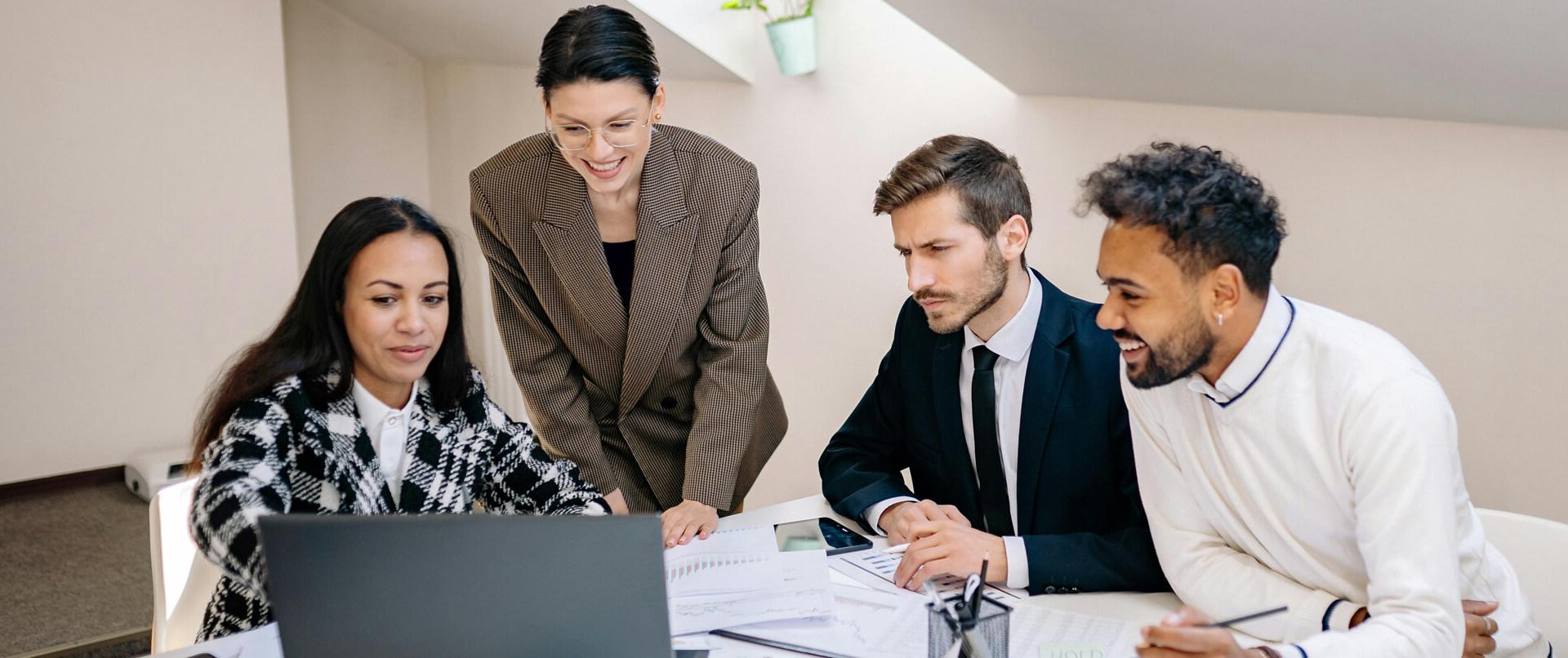 Photo of a group of people looking at a laptop.